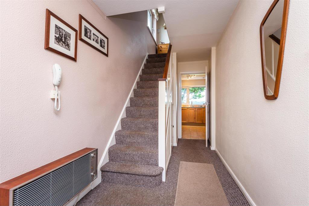 Dated carpeted staircase with white spindles in a Nottingham hallway before remodelling